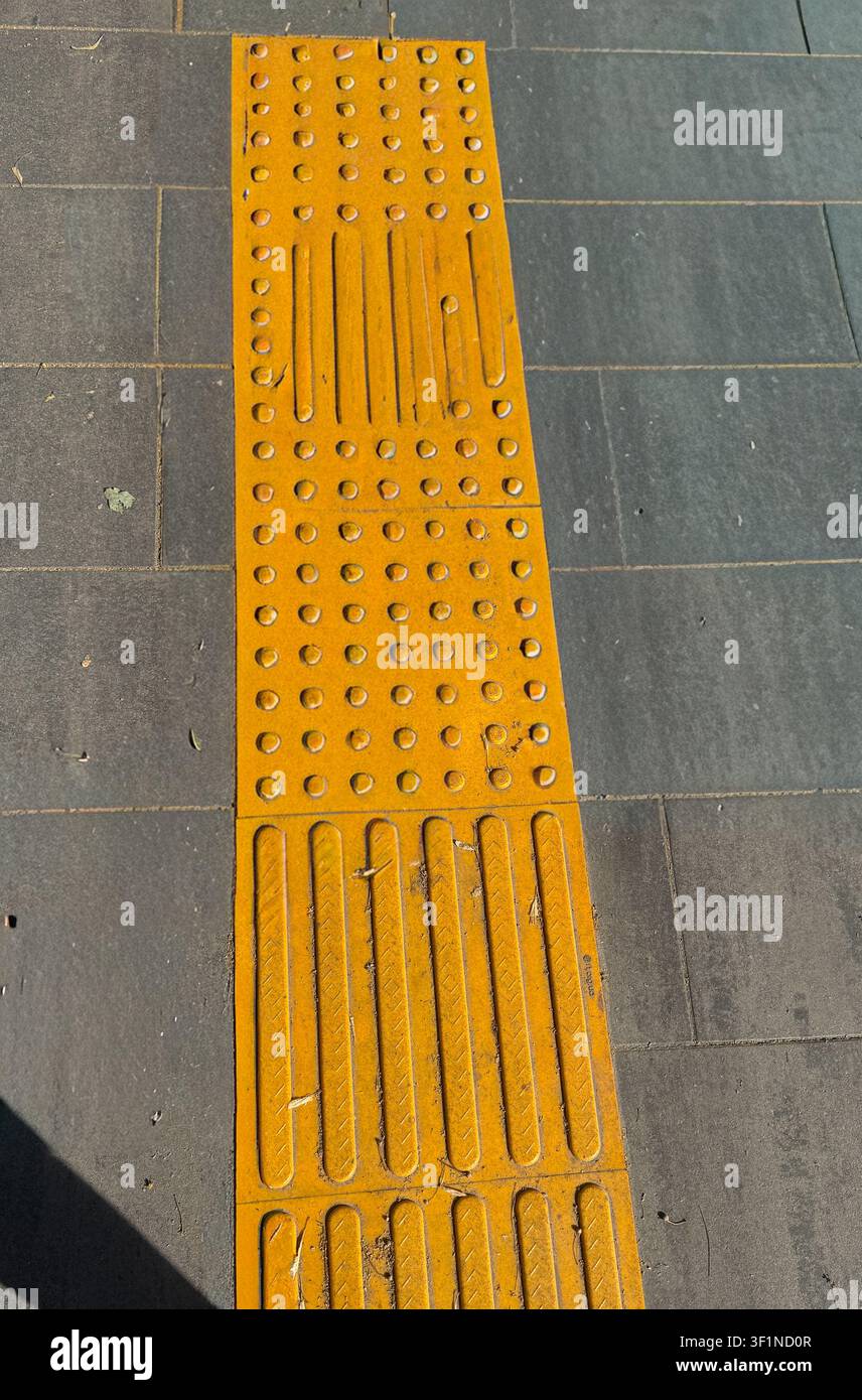 Carreaux de pavage tactiles pour personnes malvoyantes sur un trottoir gris. - Image de stock capturée avec un smartphone