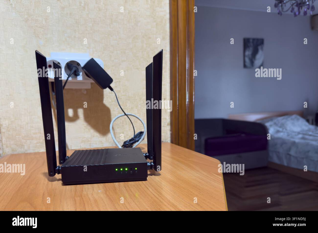 Routeur Wi-Fi sans fil noir avec plusieurs antennes sur une table en bois dans un cadre domestique. Banque D'Images