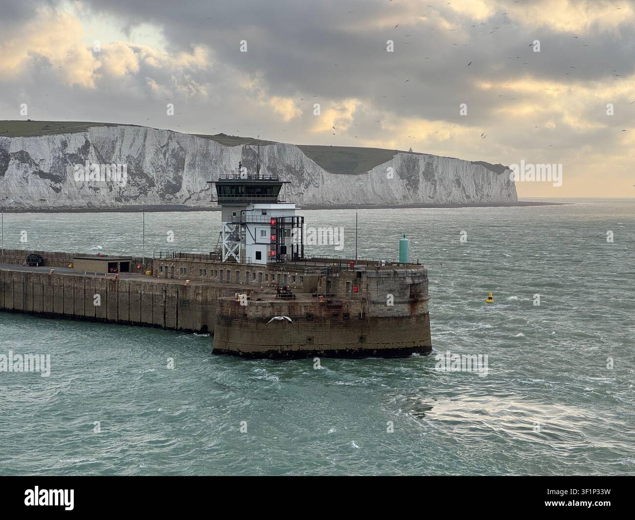 Un brise-lames s'étend dans la mer au port de Dover et les falaises blanches emblématiques en arrière-plan. Le ciel est sombre au petit matin - Image de stock capturée avec un smartphone