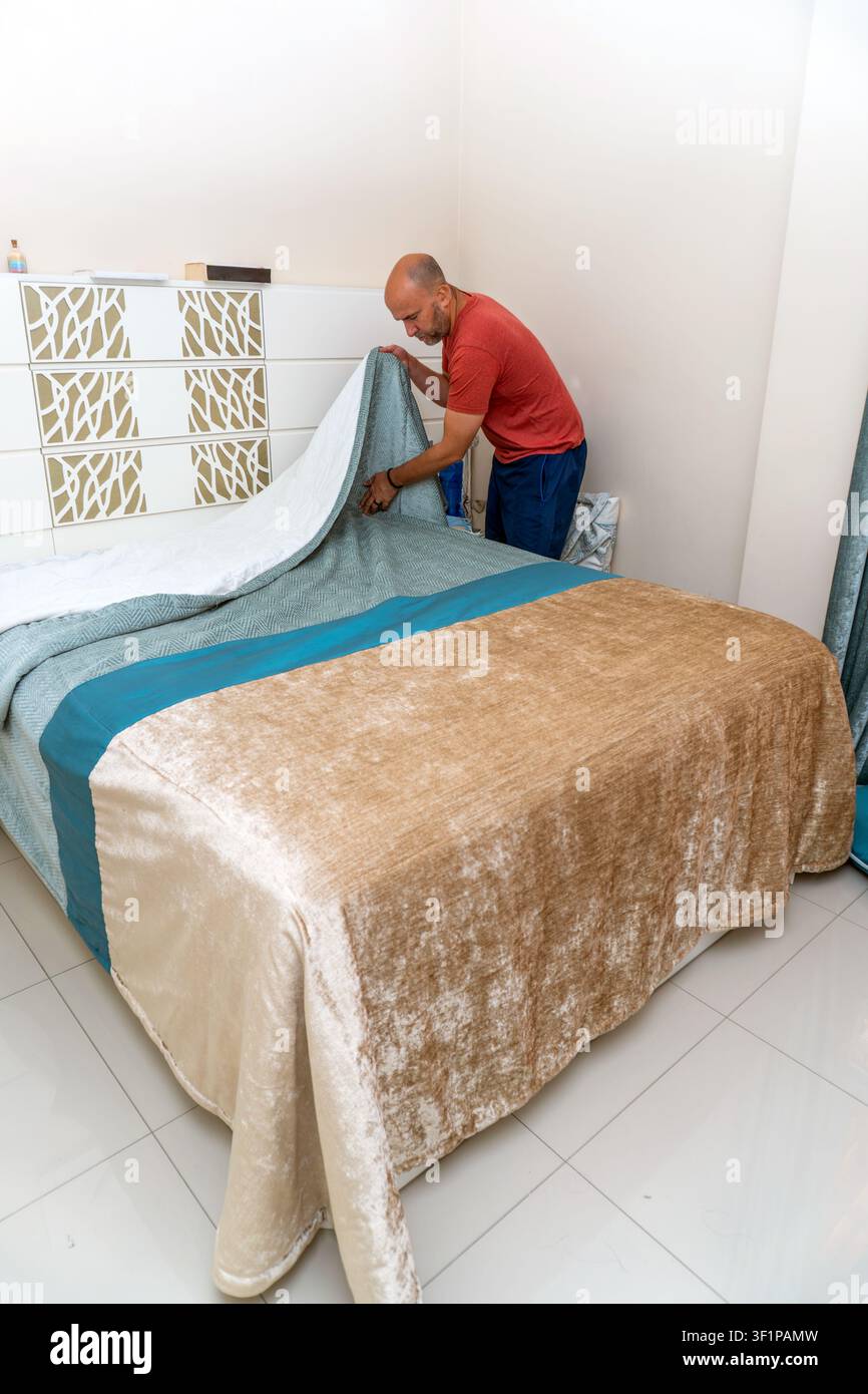 Homme faisant le lit, rangeant la chambre, faisant des tâches ménagères Banque D'Images