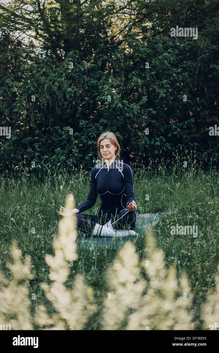 Jeune femme méditant en plein air sur un tapis de yoga. Routine de soins personnels, mode de vie de détox numérique, méditation pour les débutants. Banque D'Images