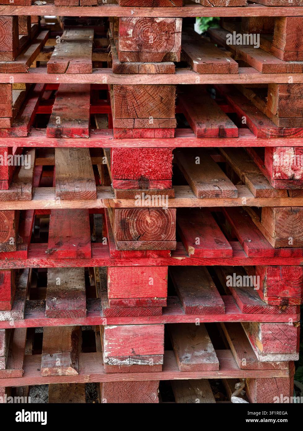 Palettes en bois patinées empilées verticalement à l'extérieur montrant une texture de bois vieillie et des lattes géométriques répétitives créant un aspect industriel brut Banque D'Images