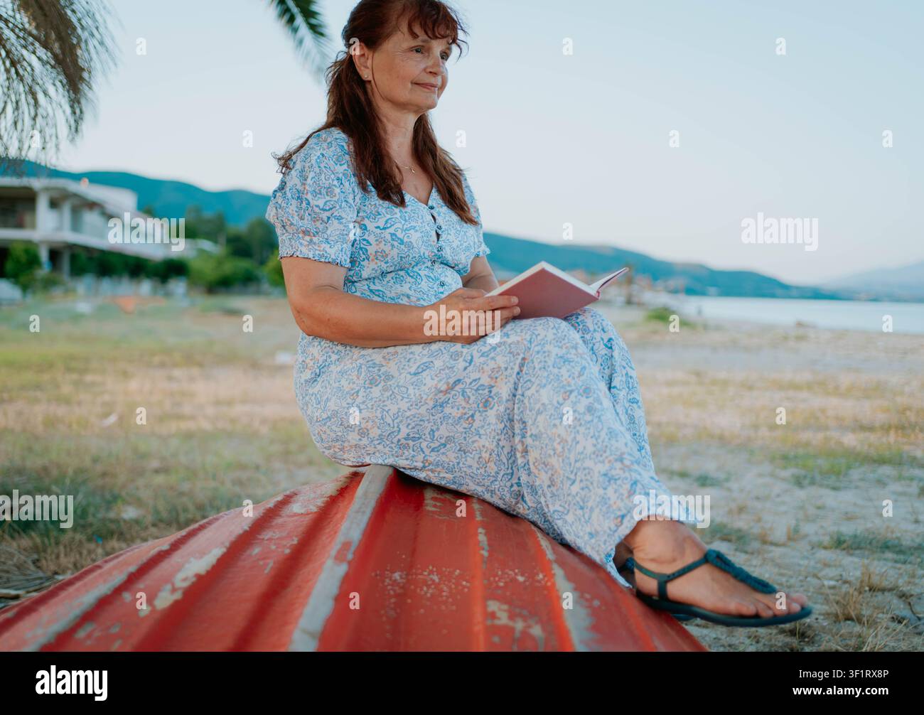 FEMME ÂGÉE AVEC UN LIVRE SUR LA PLAGE Banque D'Images