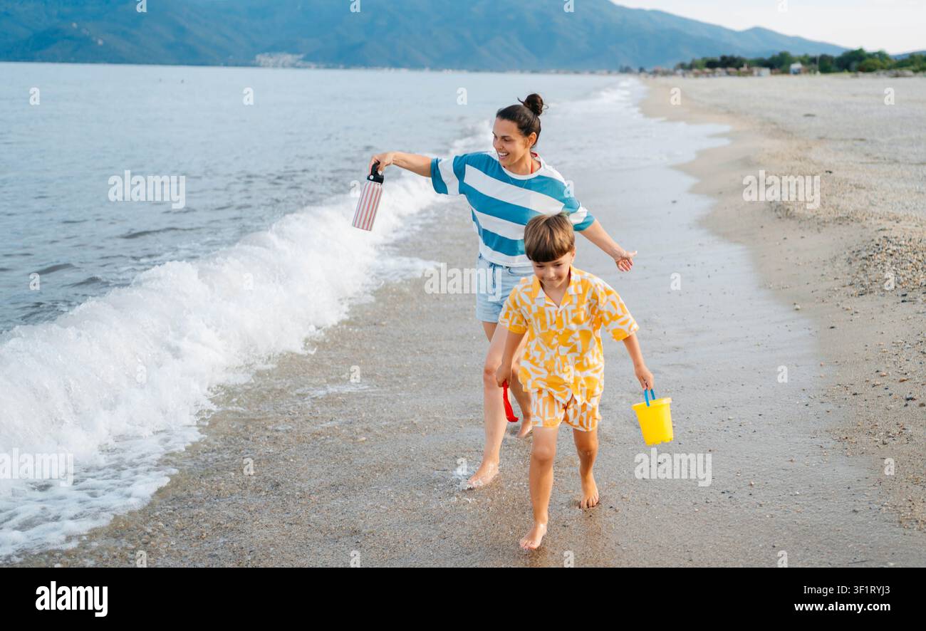 Mère et fils courant ensemble sur Sunset Beach Banque D'Images