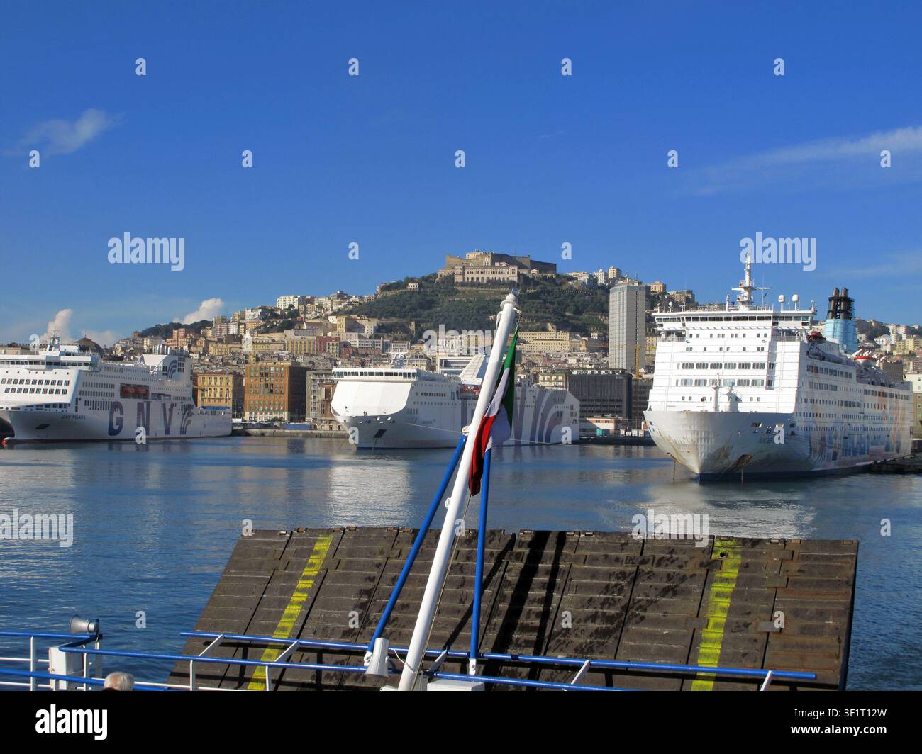 Vue lointaine du Castel Sant'Elmo avec le drapeau italien devant une rampe d'embarquement de ferry surélevée à Naples (Italie) Banque D'Images