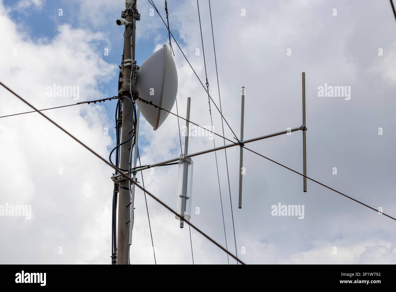 Poteau de télécommunication avec diverses antennes et câbles pour la transmission des signaux Internet, téléphoniques et de données contre un ciel nuageux Banque D'Images