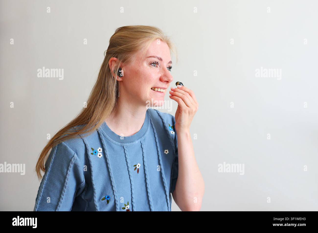 Femme utilisant des écouteurs Bluetooth pour le travail à distance, les réunions en ligne, le streaming de musique ou la communication mains libres. Banque D'Images