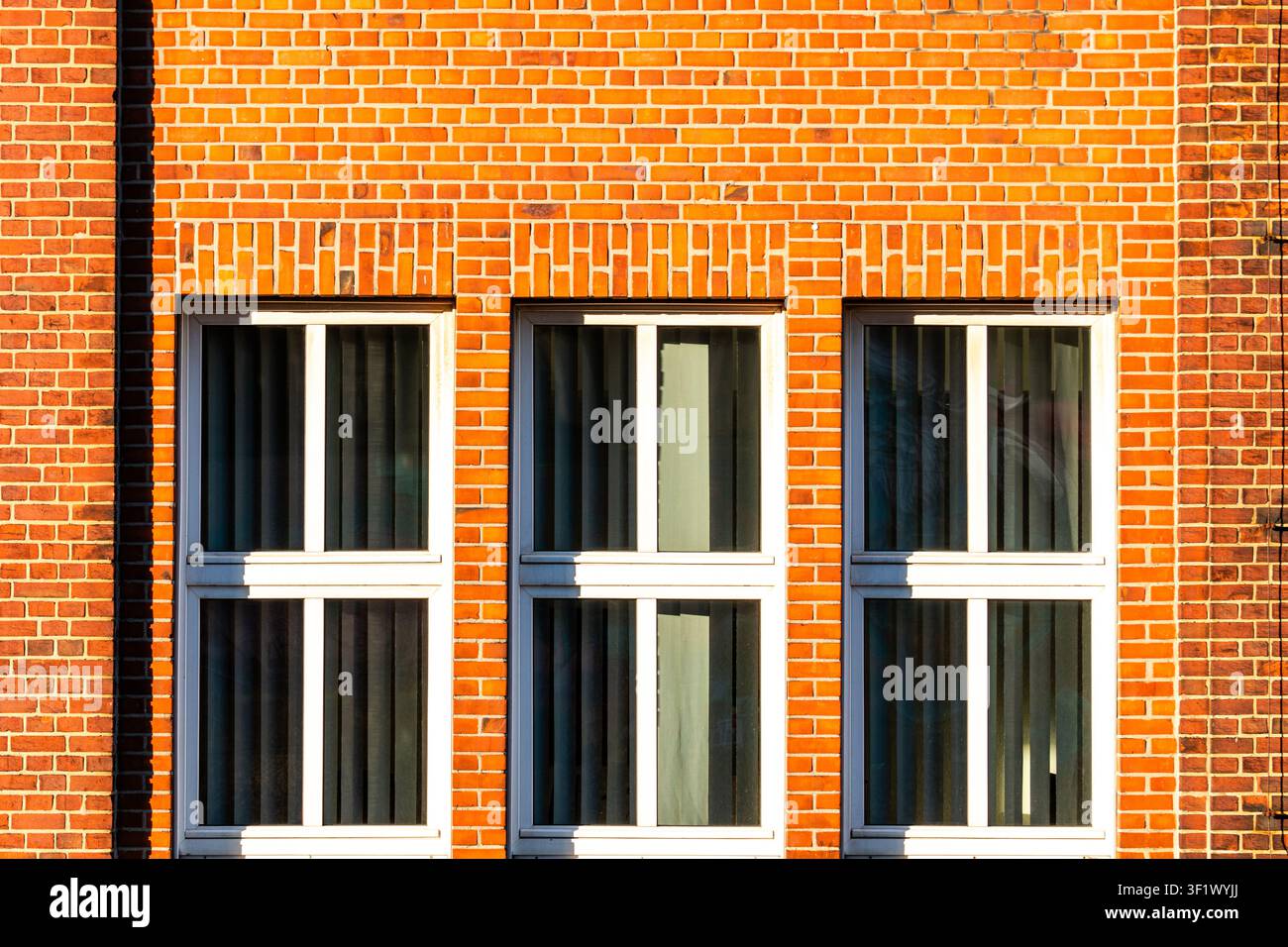 Façade symétrique en briques rouges avec trois fenêtres Banque D'Images