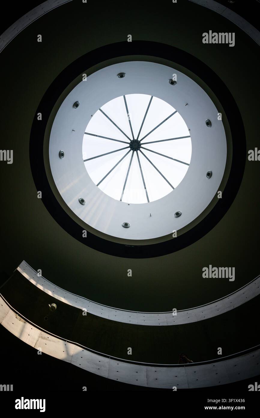 Un escalier en colimaçon menant à un puits de lumière circulaire dans un espace intérieur à Daliang, Guangdong, Chine. Banque D'Images