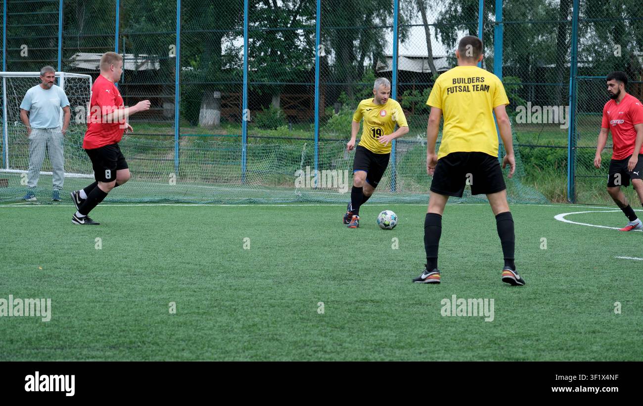 KIEV, UKRAINE - 5 juillet 2026 : Un joueur avance avec le ballon tandis que ses coéquipiers et ses adversaires se positionnent pour la prochaine action lors d’un futsal amateur en plein air Banque D'Images