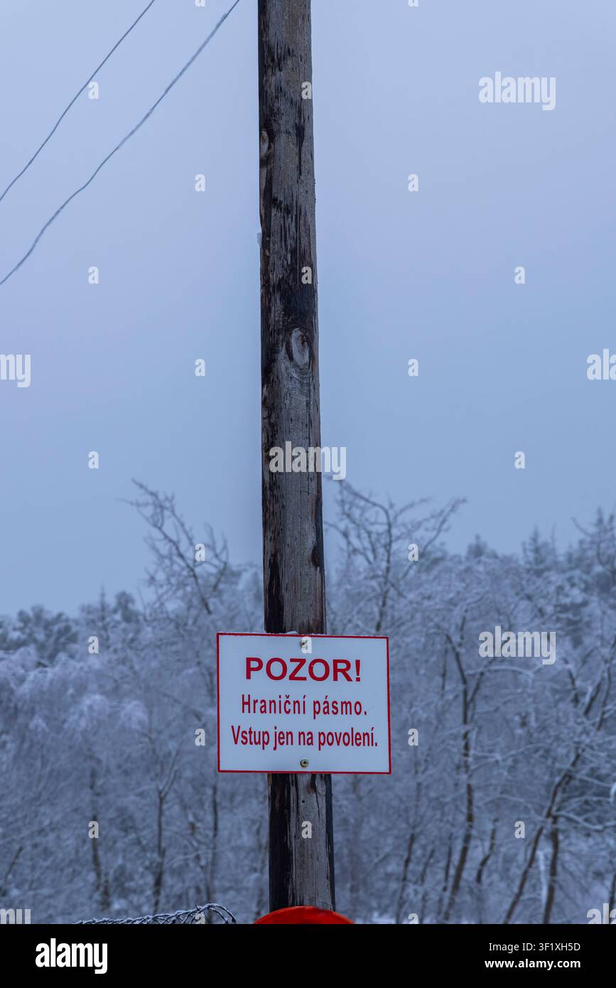 Panneau d'avertissement sur un poteau en bois indiquant une zone frontalière restreinte dans la neige à Slavonice, Tchéquie Banque D'Images