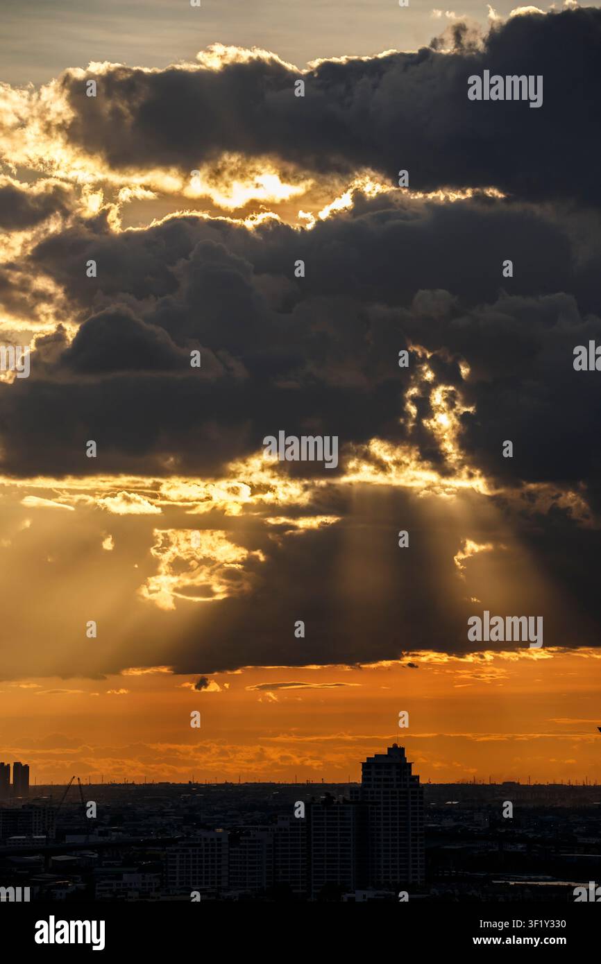 Le soleil brille intensément alors qu'il se couche à travers les nuages superposés. Banque D'Images