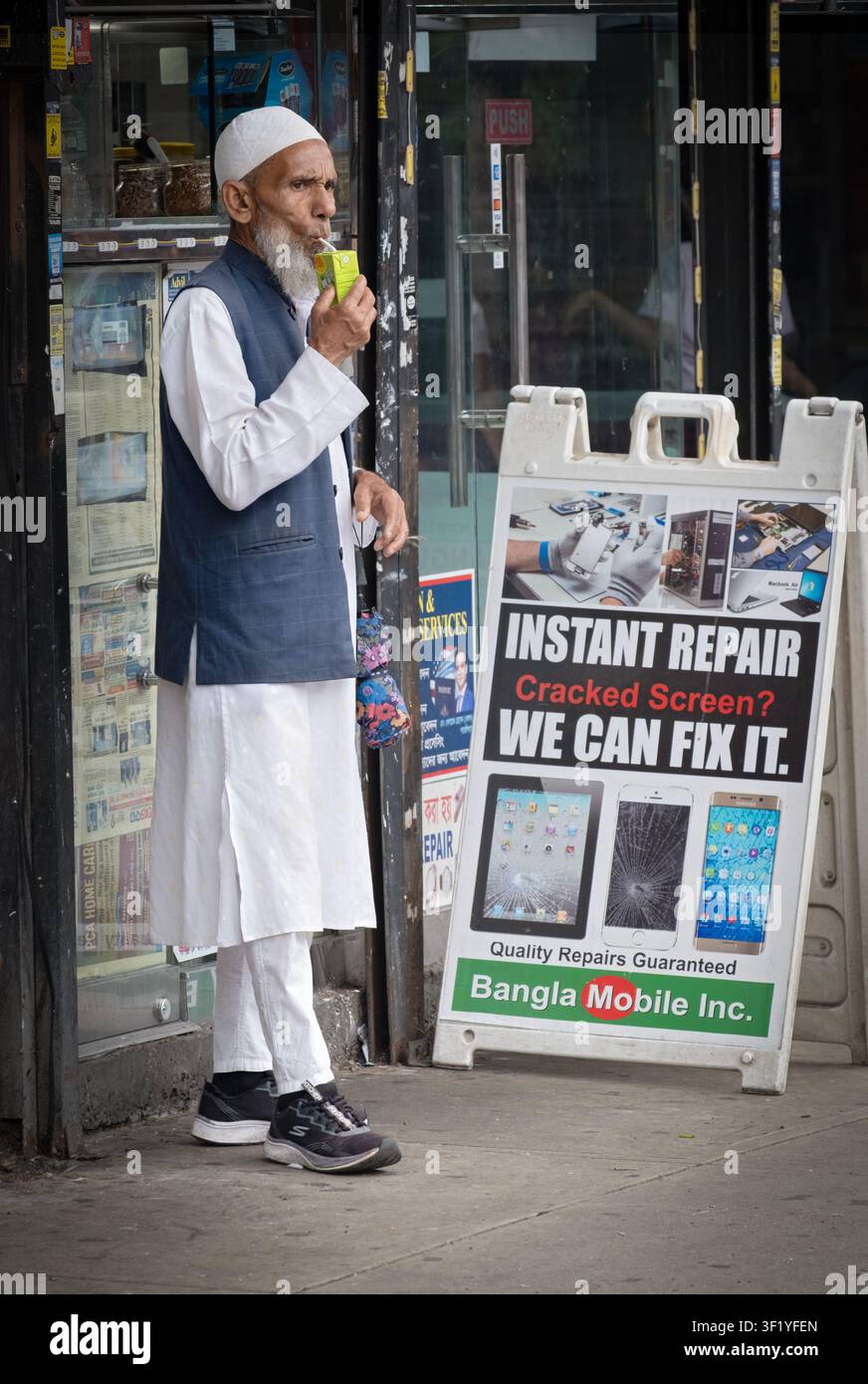 Un homme musulman âgé buvant un échantillon gratuit de jus à travers une paille à Diversity Plaza, Jackson Heights, Queens, New York. Banque D'Images