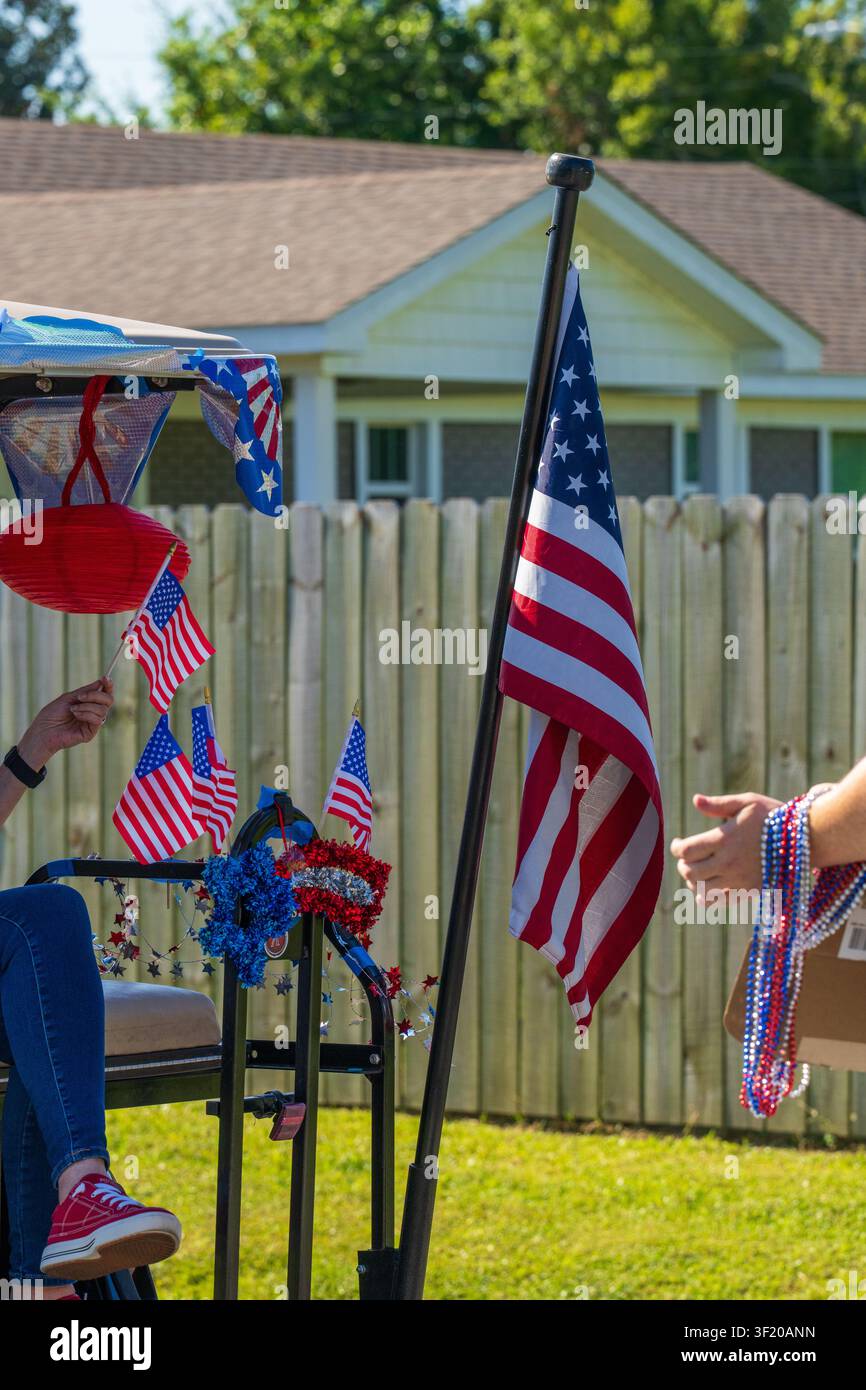 Chariot de golf décoré de drapeaux américains et de perles patriotiques célébrant un défilé de quartier du Quatre-Juillet par une journée ensoleillée. Banque D'Images