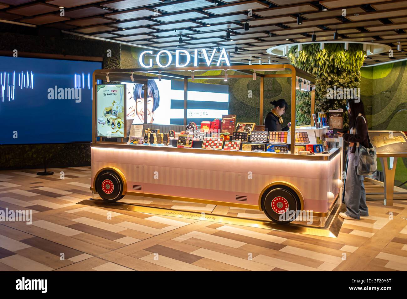 Kiosque à chocolat Godiva conçu pour ressembler à un bus vintage, avec une façade rose pastel et un éclairage intérieur vif. Hong Kong Banque D'Images