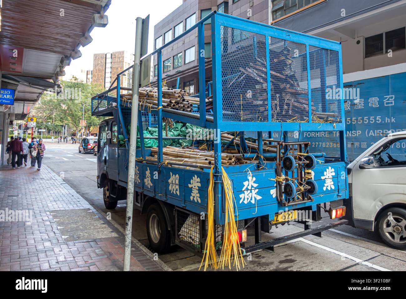 Camion bleu commercial spécialisé pour le transport de poteaux en bambou pour les échafaudages traditionnels à Hong Kong Banque D'Images