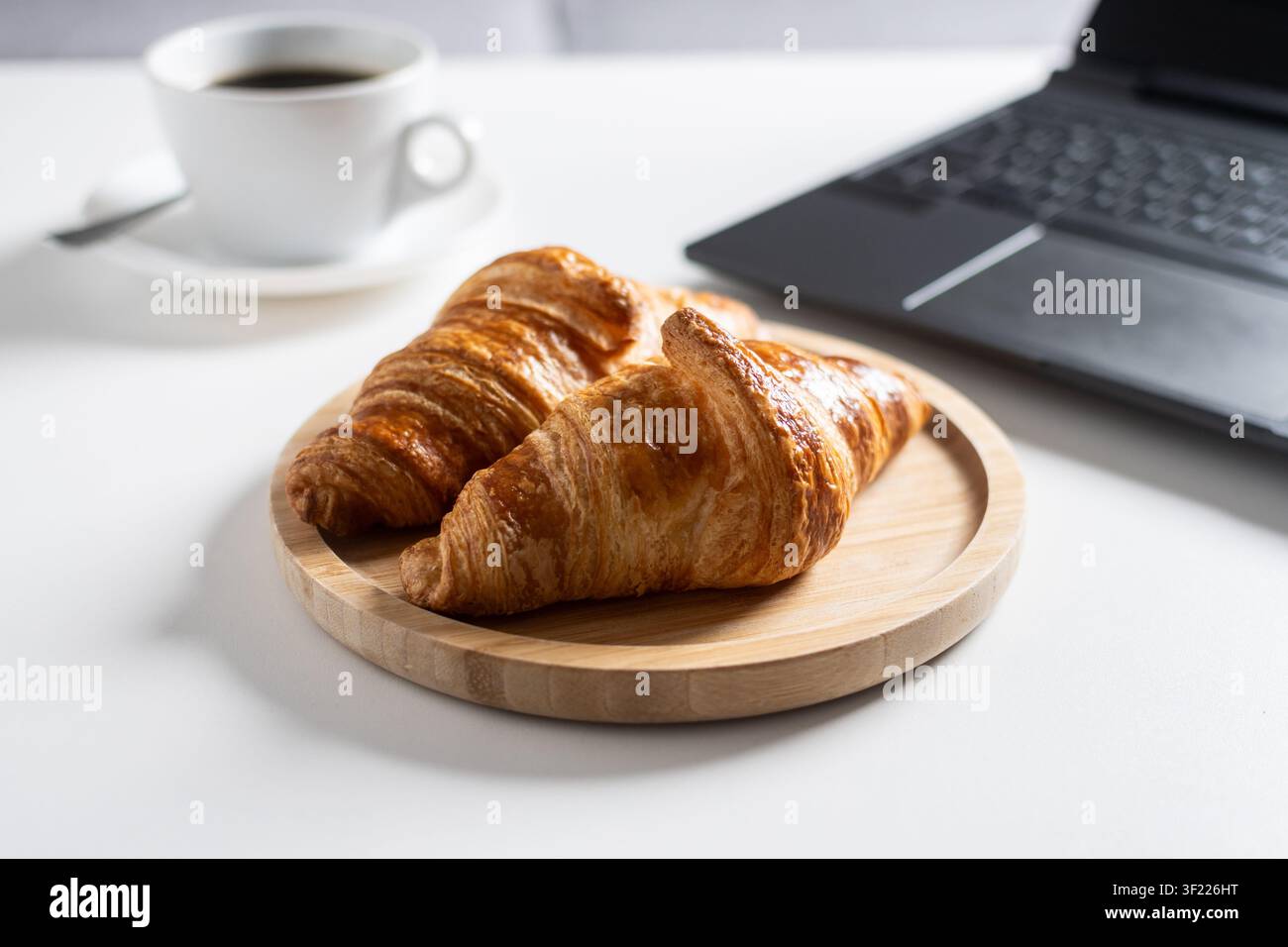 Petit-déjeuner avec café et croissants sur le bureau à domicile. Banque D'Images
