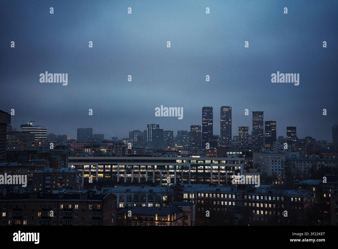 Vue nocturne des gratte-ciel et des immeubles résidentiels sous un ciel bleu foncé. Horizon urbain avec des fenêtres lumineuses. Banque D'Images