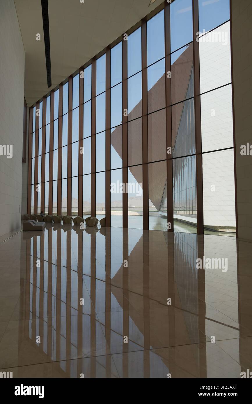 Un espace intérieur minimaliste à Nizwa, Oman, présentant des murs en verre, des lignes géométriques fortes, un sol réfléchissant et une façade contemporaine sculpturale Banque D'Images