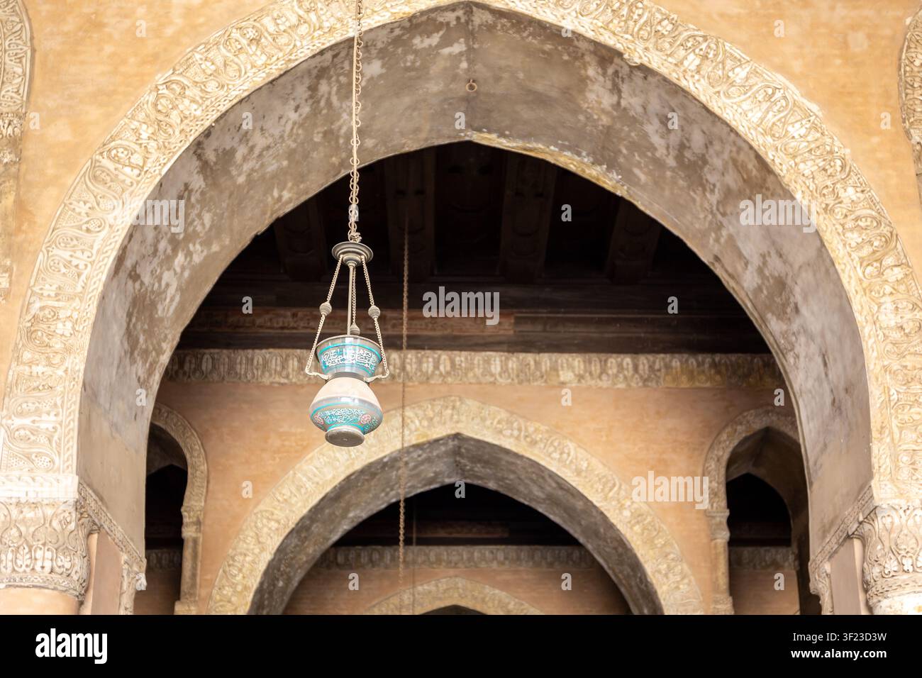 Le Caire, Égypte, 26.07.21. Arches pointues ornées de décorations en stuc sculpté et lampe arabe suspendue avec inscriptions dans la mosquée d’Ibn Tulun au Caire, Égypte Banque D'Images