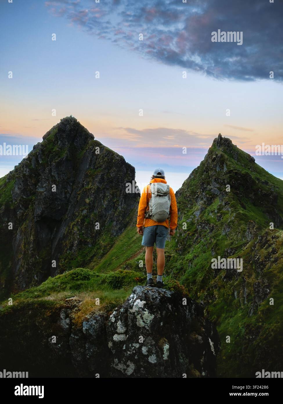 Touriste masculin debout seul dans les montagnes, voyage en Norvège, aventure en solo d'escalade, vacances d'été, tour en plein air, randonneur avec sac à dos profitant du coucher de soleil L Banque D'Images