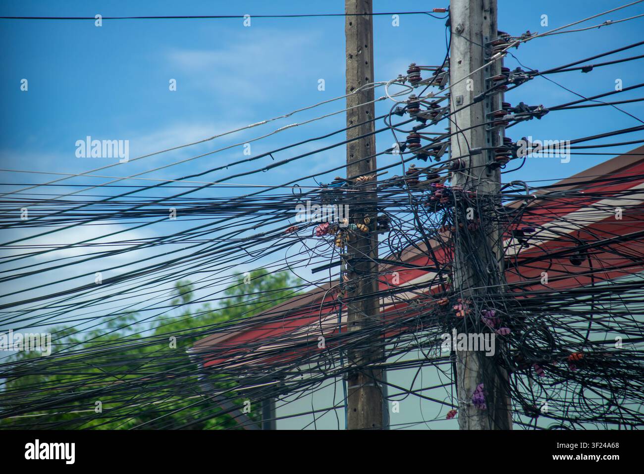 Cette image présente des poteaux électriques chargés de fils électriques, de câbles téléphoniques et de câbles de communication, illustrant l'infrastructure urbaine et la complexité Banque D'Images