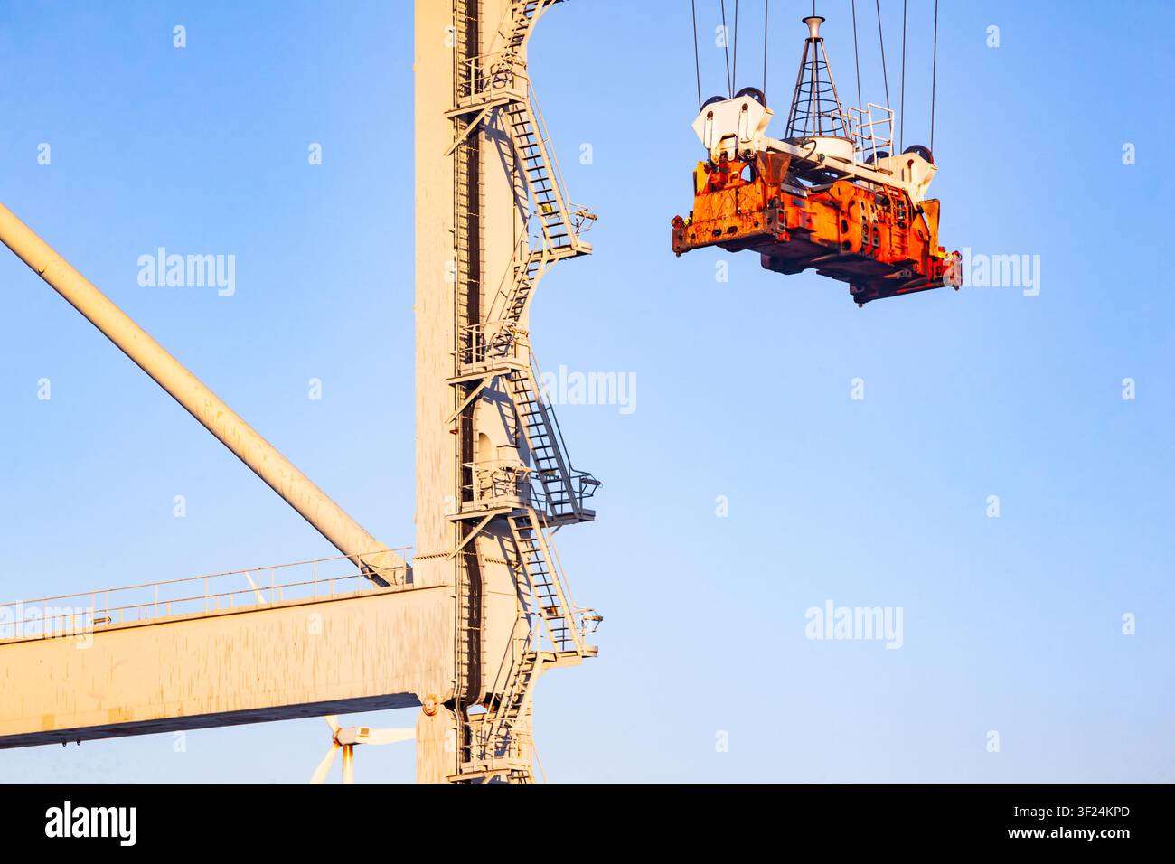 Grue portique d'un terminal de conteneurs soulevant le mécanisme de répandeur à double levage devant un ciel bleu clair pendant les opérations de manutention de chargement Banque D'Images