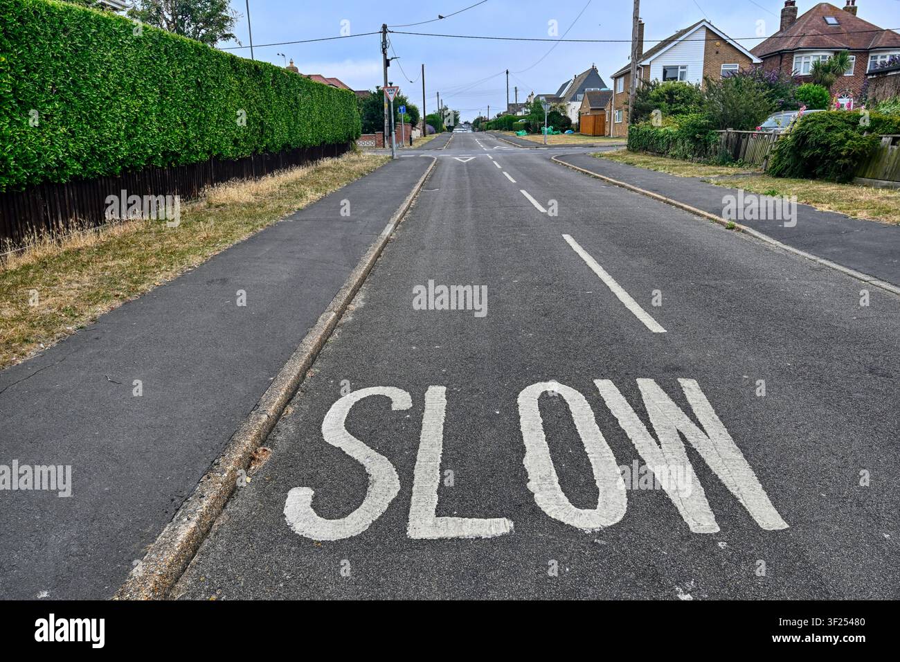 Le mot SLOW peint sur une rue calme d'une ville anglaise, Hunstanton, Norfolk, Royaume-Uni Banque D'Images
