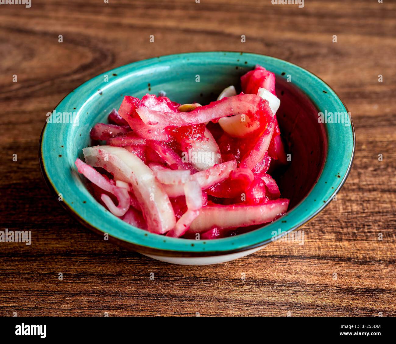 Oignons marinés turcs traditionnels avec sauce aux cerises ou vinaigrette au sumac dans un bol en céramique turquoise. Banque D'Images