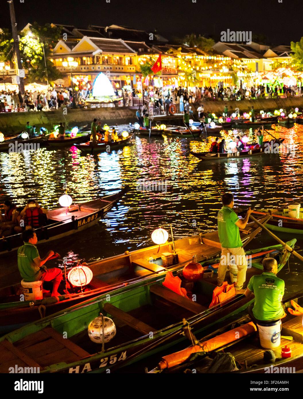 Hoi An, Vietnam – 28 juin 2025 : Après la tombée de la nuit, avec des lanternes colorées allumées, les opérateurs de bateaux fluviaux pagayent doucement les touristes lors de voyages romantiques à travers l’historique Banque D'Images
