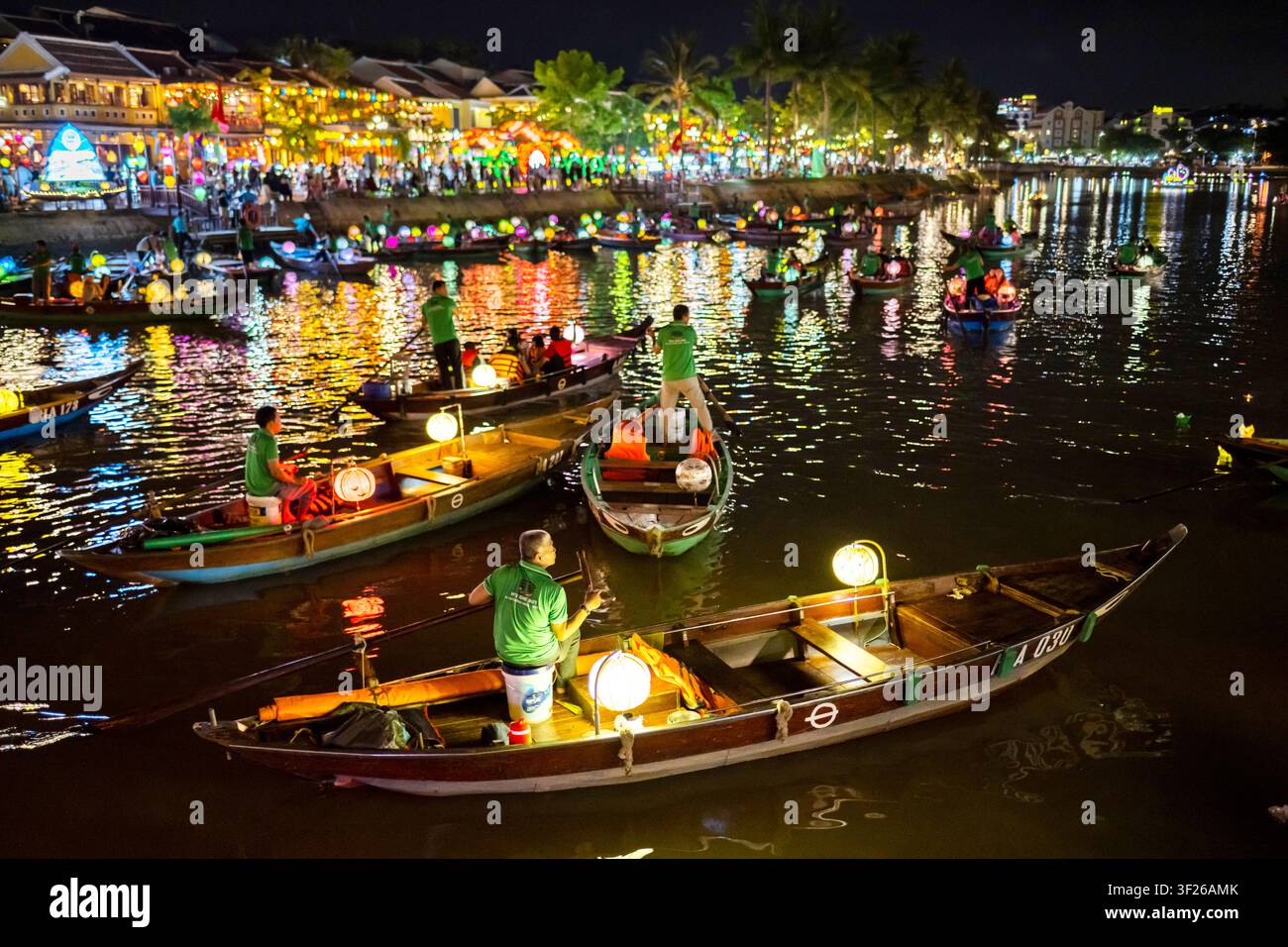 Hoi An, Vietnam – 28 juin 2025 : Après la tombée de la nuit, avec des lanternes colorées allumées, les opérateurs de bateaux fluviaux pagayent doucement les touristes lors de voyages romantiques à travers l’historique Banque D'Images