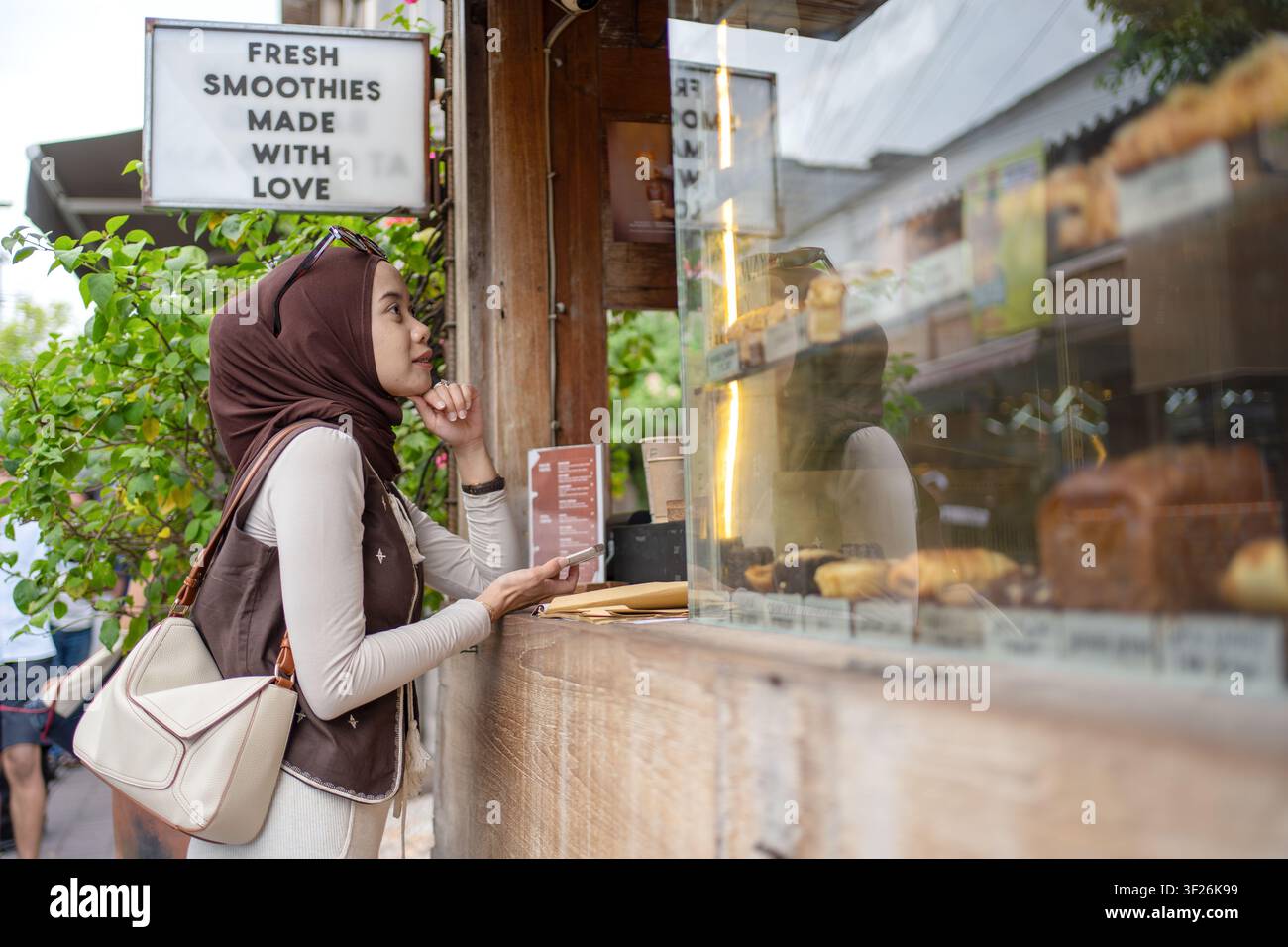 Jeune femme musulmane indonésienne choisissant des aliments dans un café boulangerie à Bali, Indonésie. Style de vie contemporain, comportement de consommation, voyage et culture du café Banque D'Images