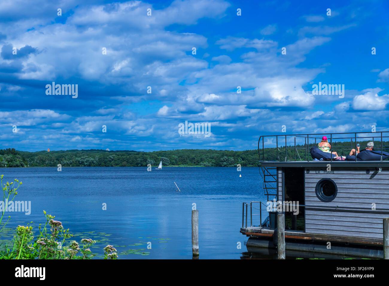 Les touristes se détendent sur la terrasse toit d'une péniche amarrée au lac Templin par une journée d'été ensoleillée. Lac de Templin, Brandebourg, Potsdam, Allemagne. Banque D'Images