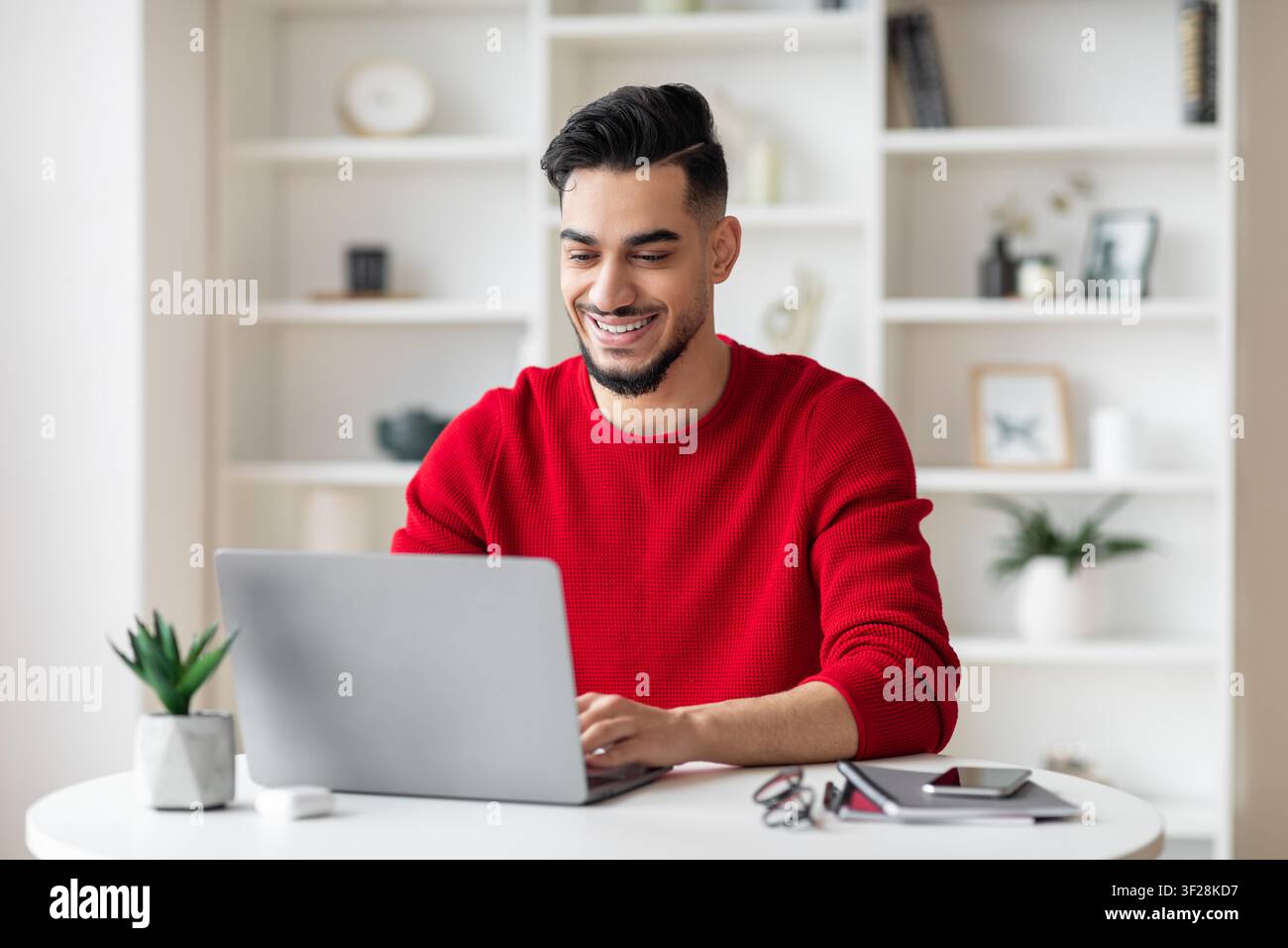 Jeune homme arabe souriant travaillant sur un ordinateur portable à la maison, concept d'affaires Banque D'Images