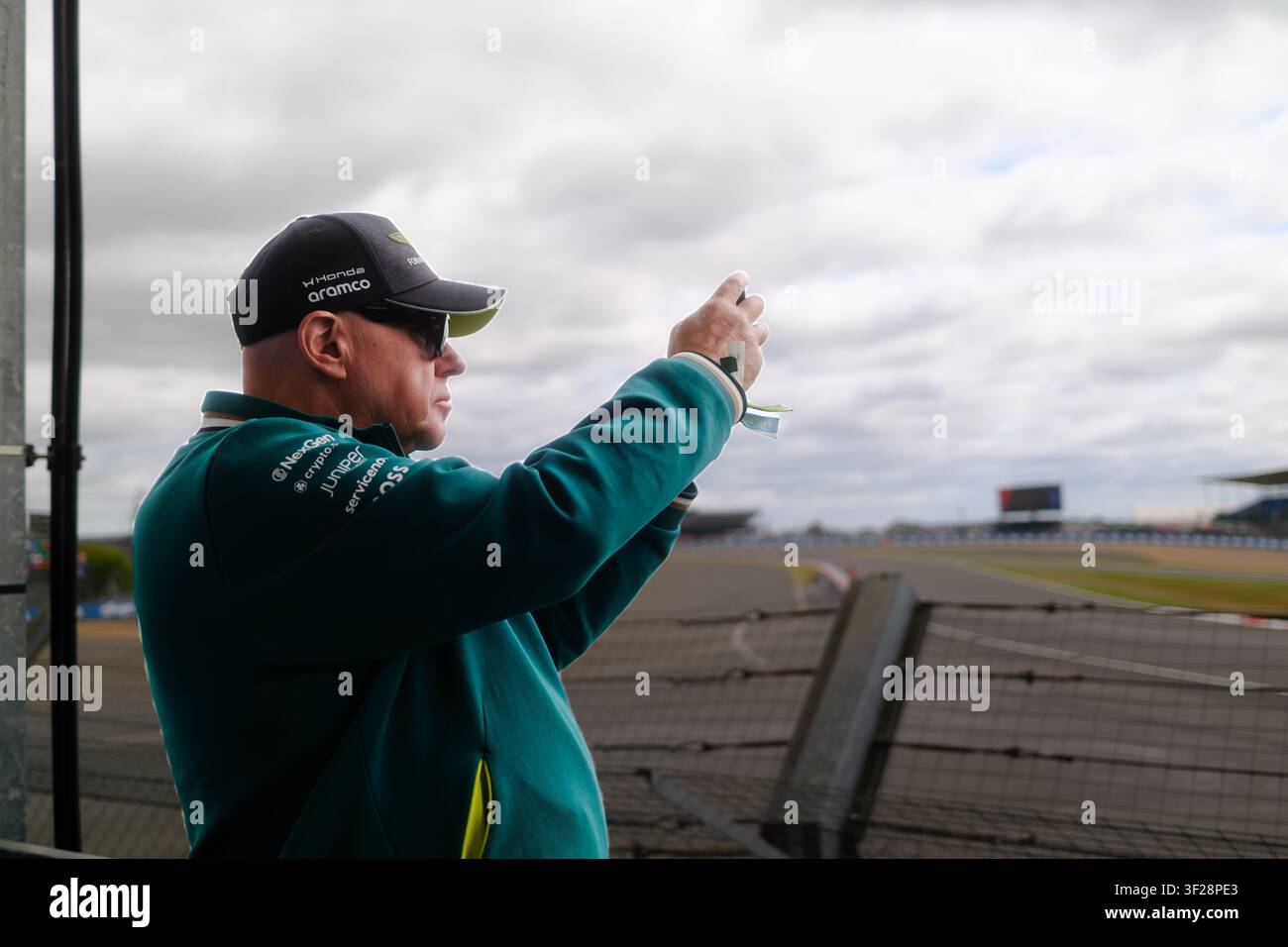 Un fan filme avec son iPhone à Silverstone pendant le Grand Prix de Grande-Bretagne, avec le circuit visible en arrière-plan Banque D'Images