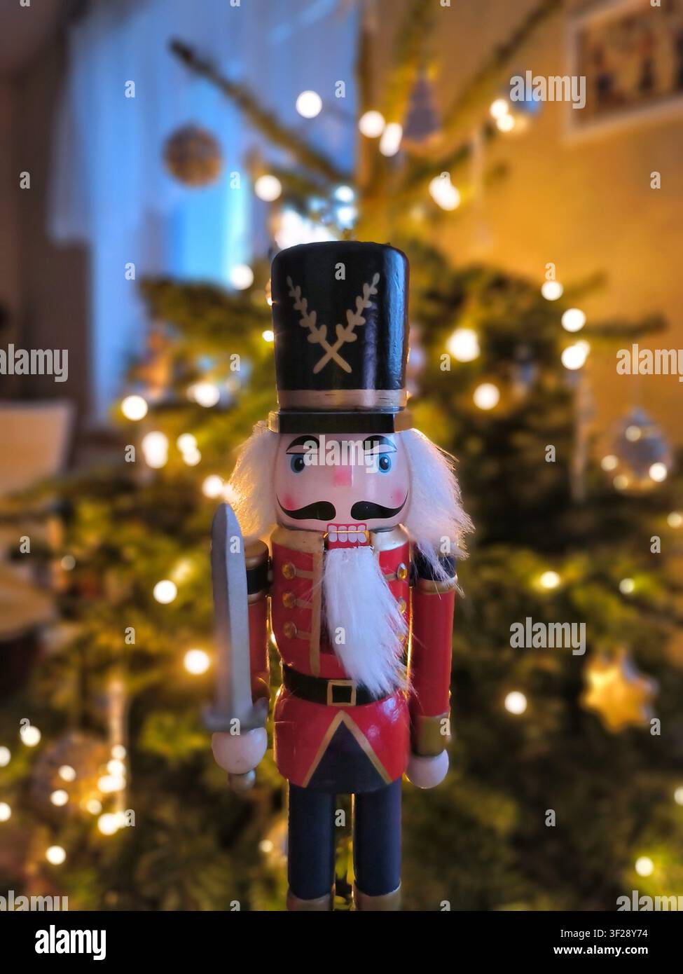 gros plan d'une poupée casse-noix rouge artisanale vintage debout dans un intérieur chaleureux avec des lumières féeriques bokeh chaudes d'un décor - Image de stock capturée avec un smartphone