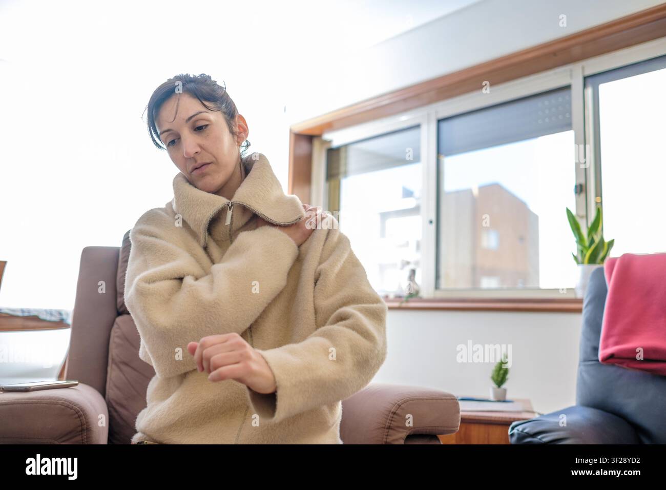 Femme ressentant une douleur à l'épaule, tenant son épaule douloureuse avec une expression de douleur Banque D'Images