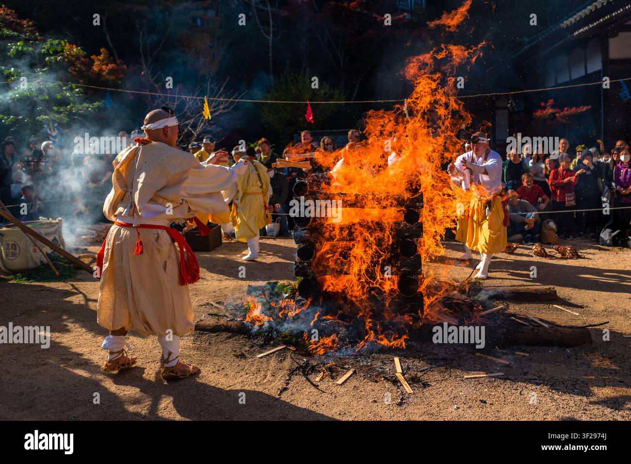 Les moines Yamabushi jettent des bâtons de prière en bois dans un feu sacré lors de la cérémonie de marche sur les braises au temple Daisho-in sur l'île de Miyajima, au Japon. Banque D'Images