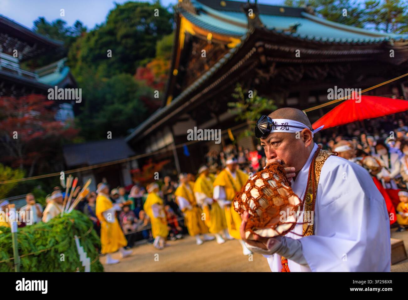 Un moine yamabushi souffle dans un horagai, une trompette en coquillage, lors de la cérémonie de marche sur le feu au temple Daisho-in sur l'île de Miyajima, au Japon. Banque D'Images