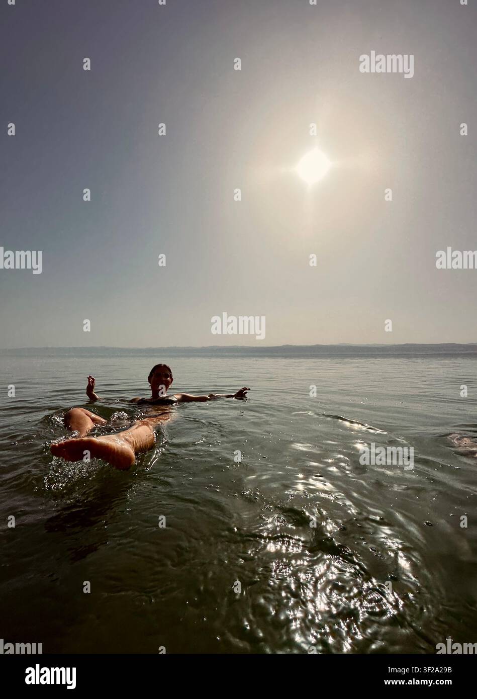 Flottant dans la mer Morte sous un soleil brumeux Banque D'Images