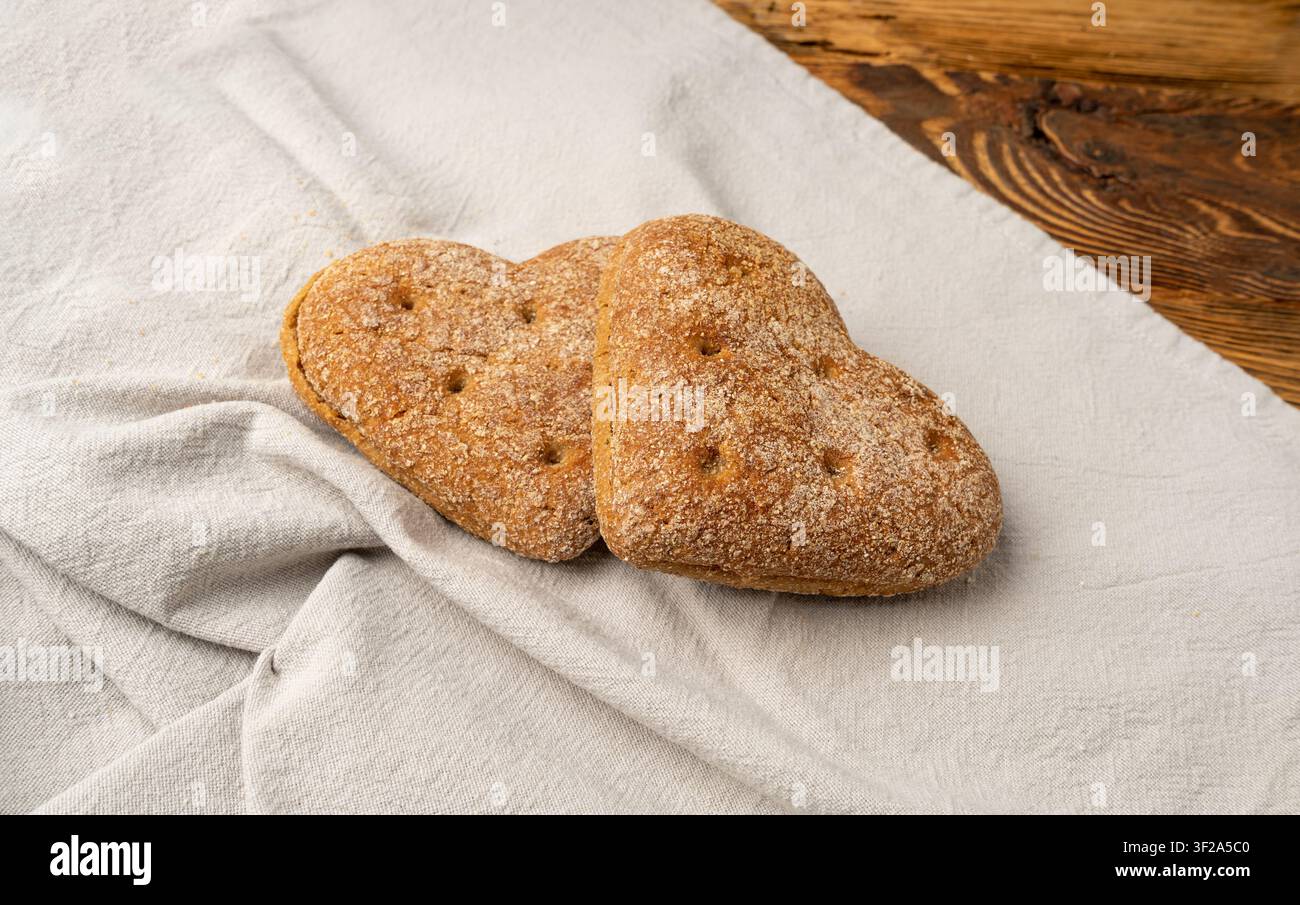 Petit pain d’avoine en forme de cœur sur une table en bois, pain plat finlandais sans gluten, pain biologique de céréales en forme de cœur sur un fond rustique Banque D'Images