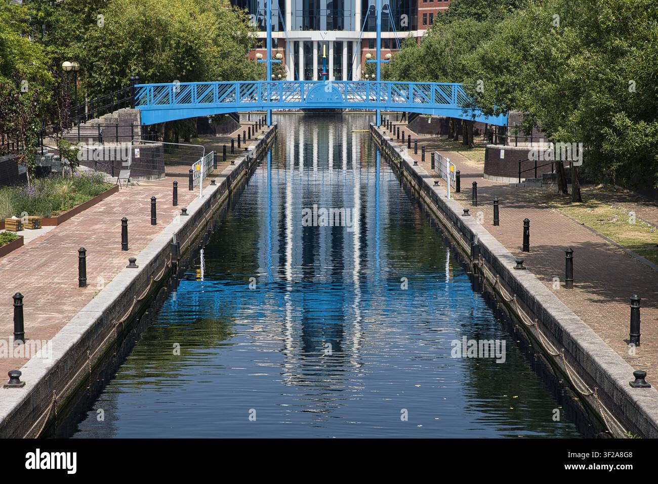 Une vue rapprochée regardant le long d'un canal mettant en scène un pont piétonnier bleu vif et son reflet dans l'eau aux Salford Quays, Salford, Royaume-Uni Banque D'Images