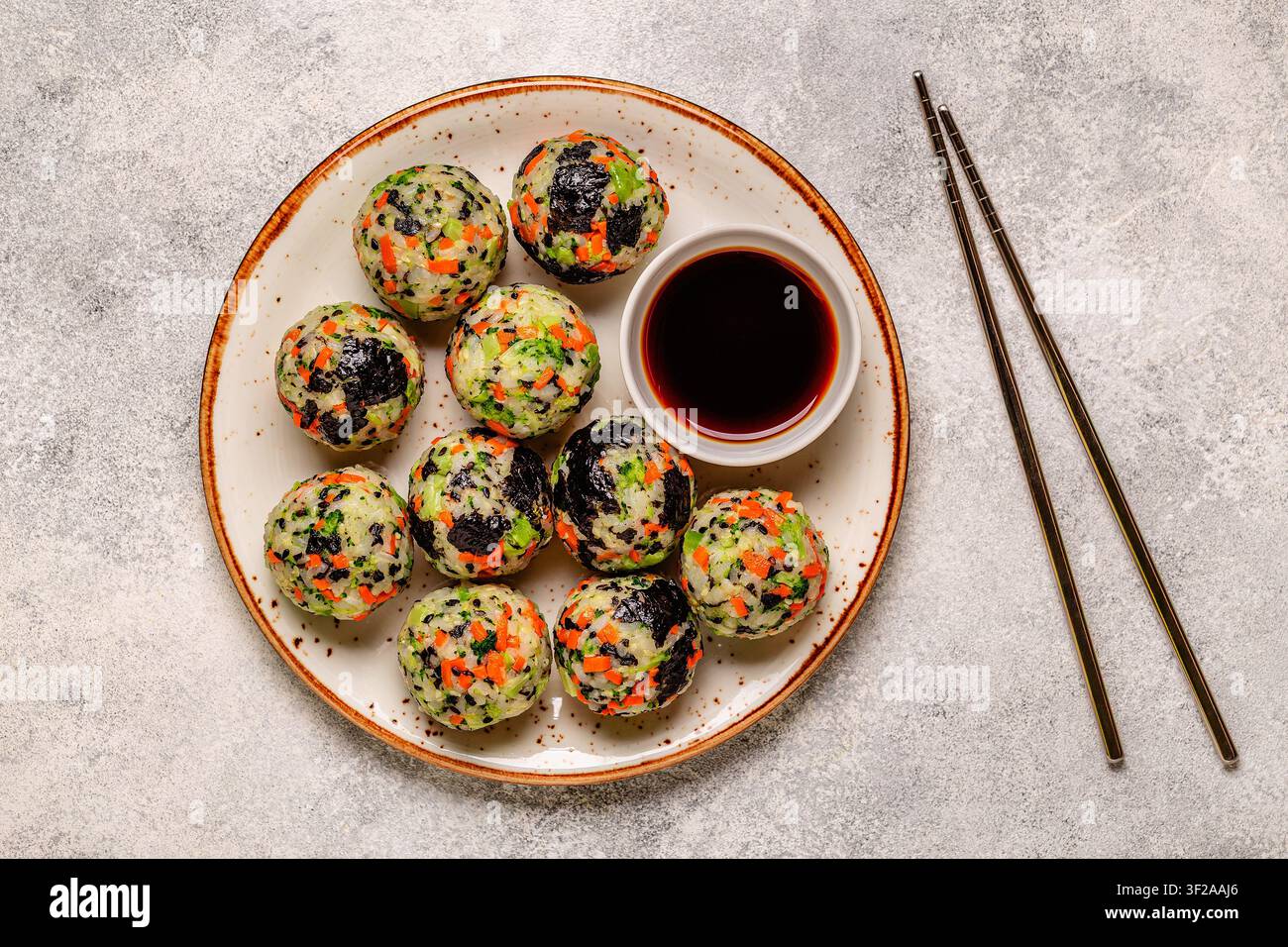 Boulettes de riz coréennes (jumeokbap) avec légumes servis avec sauce dans une assiette, vue de dessus. Banque D'Images