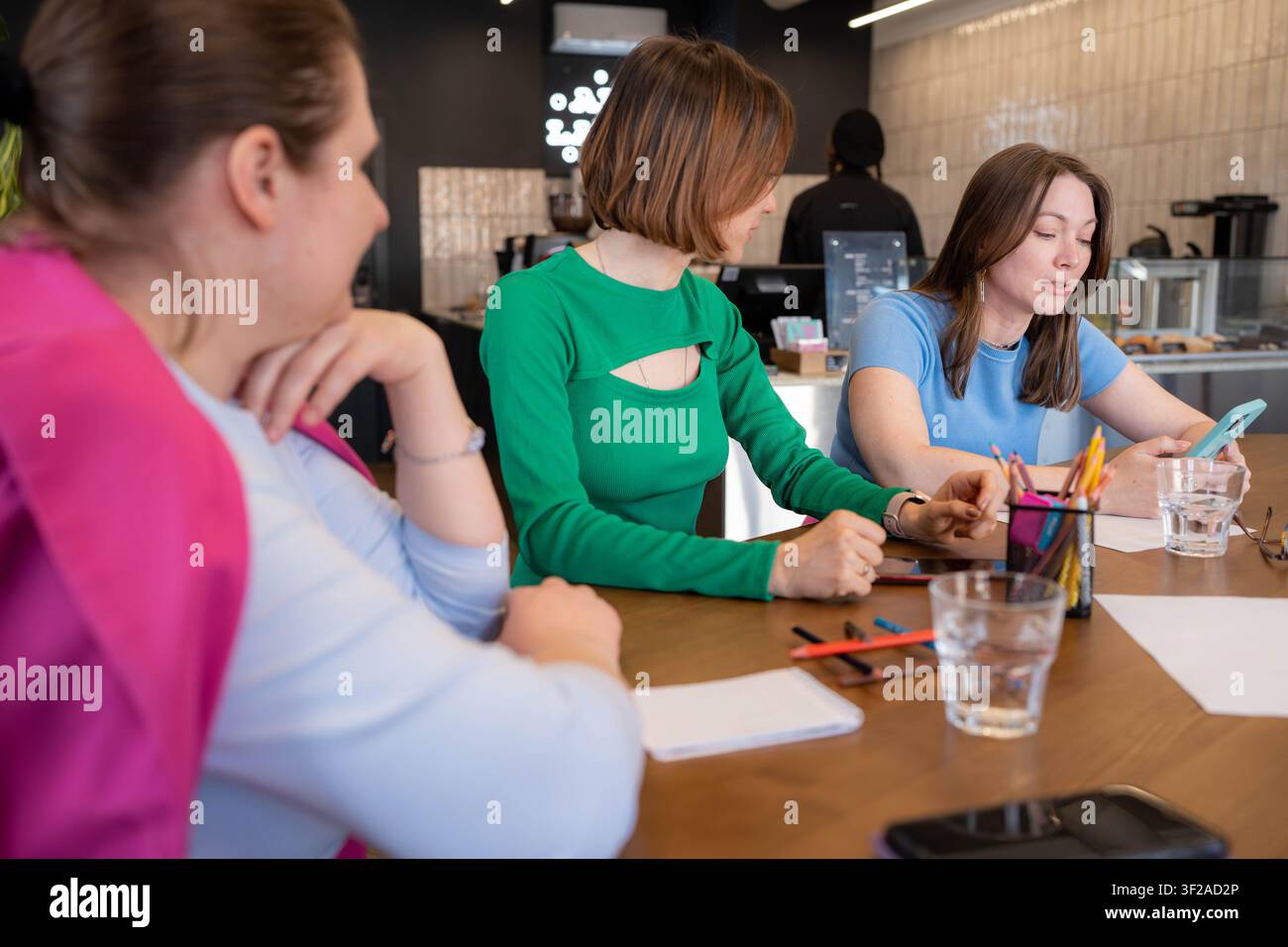Équipe créative de femmes à une table de café dessinant, écrivant et discutant des plans avec du café. Créatif, dessin, discussion, café, équipe. Banque D'Images