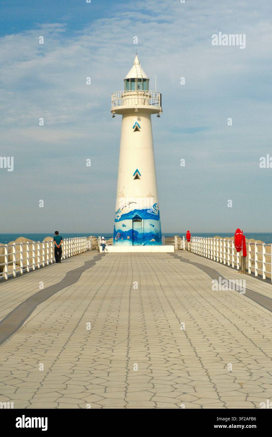 Busan, Corée du Sud – 30 mai 2026 : Le phare blanc de Cheongsapo au bout d'une jetée, avec des visiteurs marchant le long de la promenade. Banque D'Images