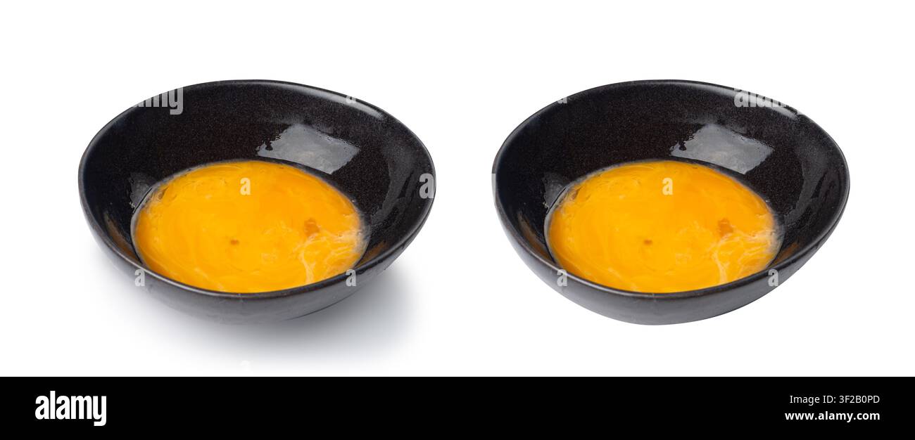 Jaunes d'œufs battus dans un bol, œufs de poule frais pour recette de cuisine, jaunes d'œufs biologiques mélangés dans un bol noir Banque D'Images