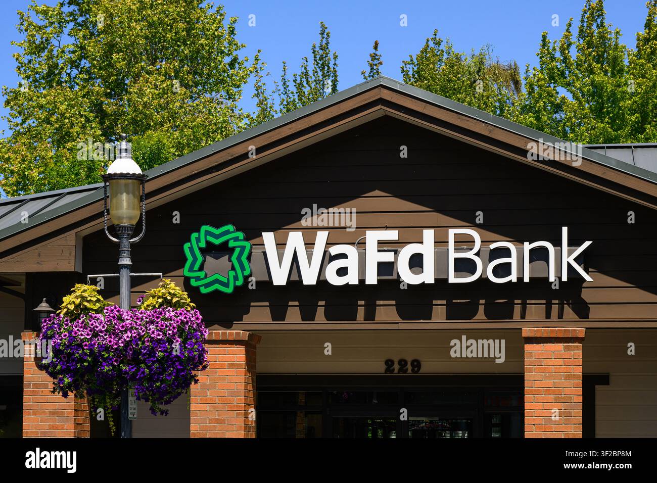 Edmonds, WA, États-Unis - 13 juillet 2026 ; Panneau sur le bâtiment de la succursale de la banque WaFd, anciennement Washington Federal, avec logo et fleurs colorées Banque D'Images