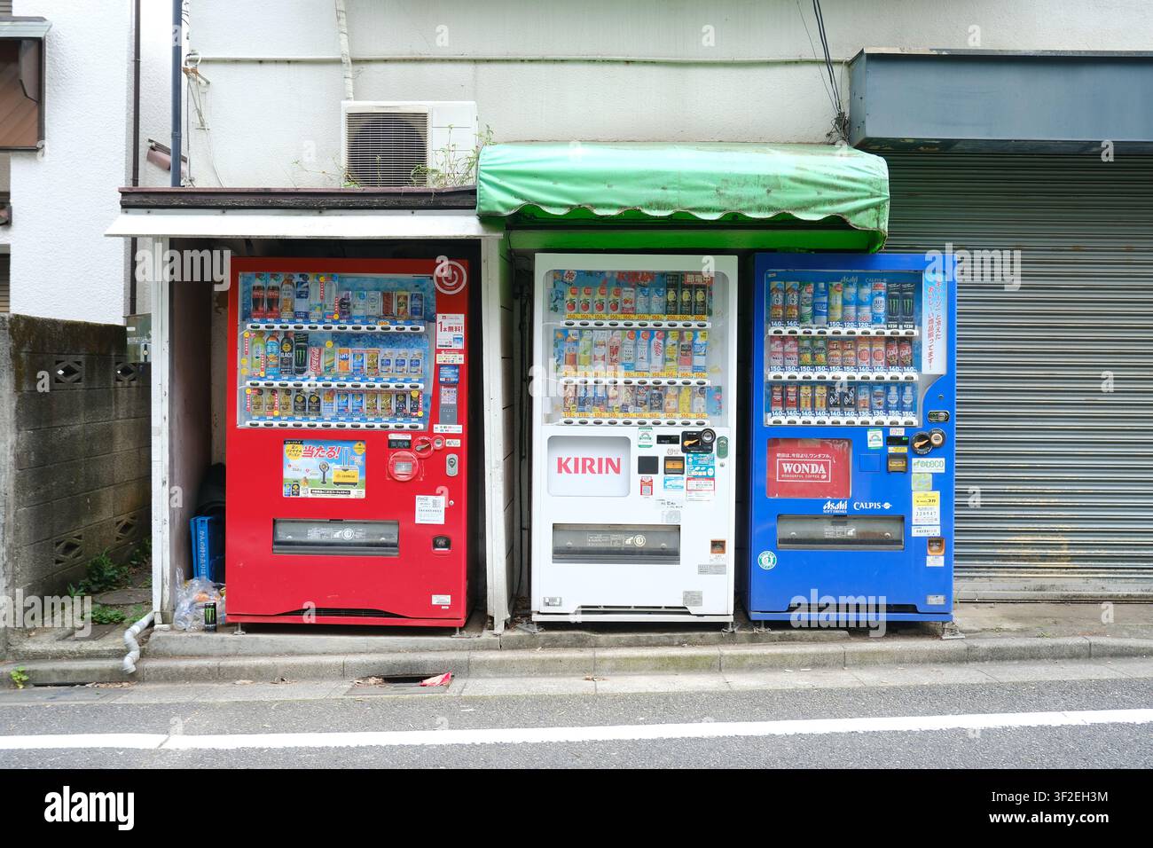 Une rangée de distributeurs de boissons colorés alignés le long d'une rue à Tokyo, au Japon Banque D'Images