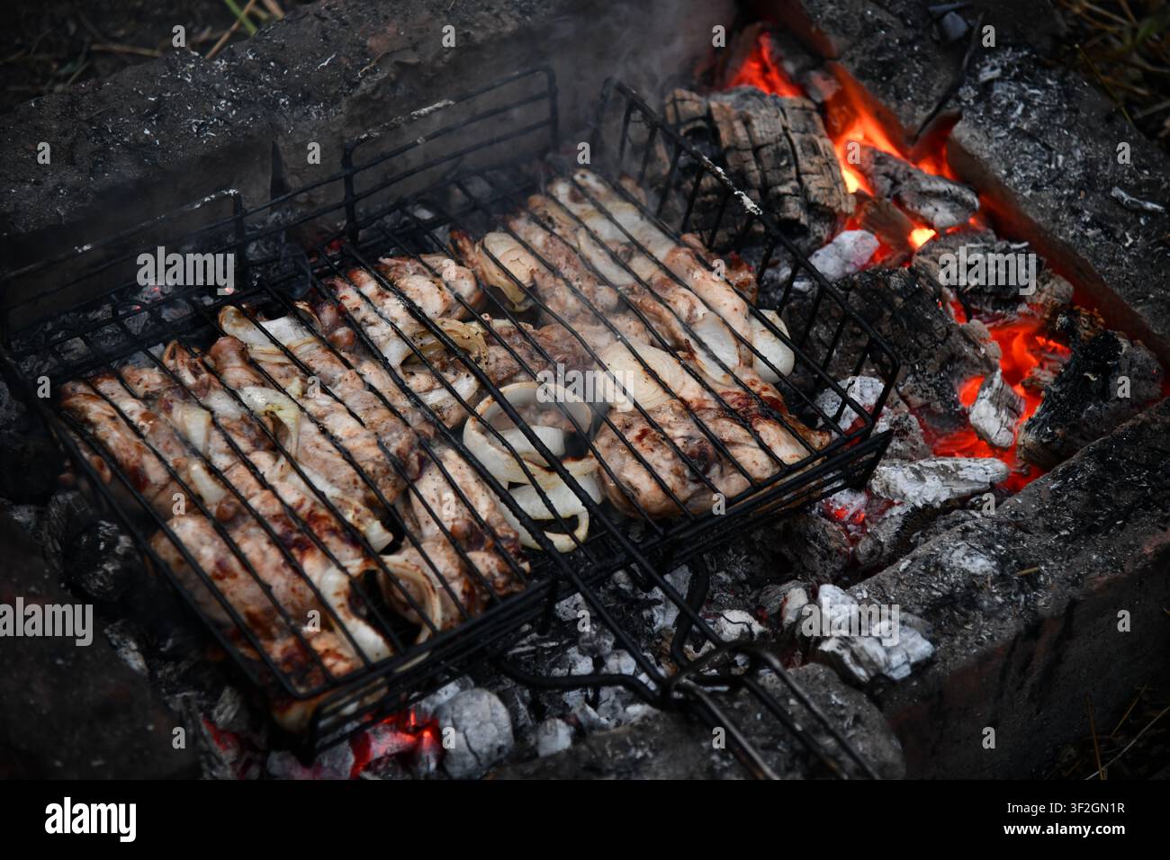 Barbecue portatif chaud et vide avec feu flamboyant et charbon de bois sur fond noir. En attente de l'emplacement de vos aliments. Gros plan Banque D'Images
