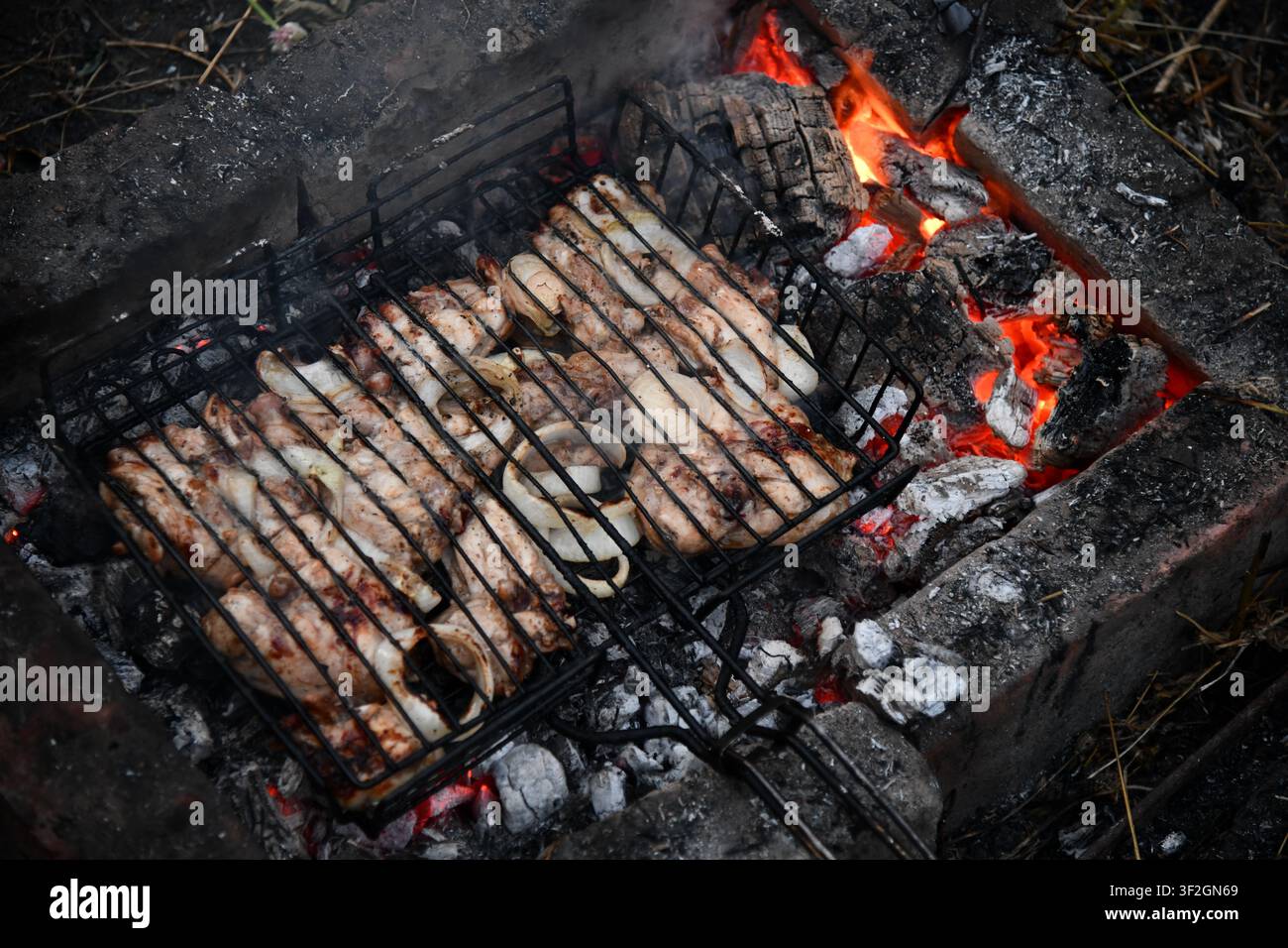 Barbecue portatif chaud et vide avec feu flamboyant et charbon de bois sur fond noir. En attente de l'emplacement de vos aliments. Gros plan Banque D'Images